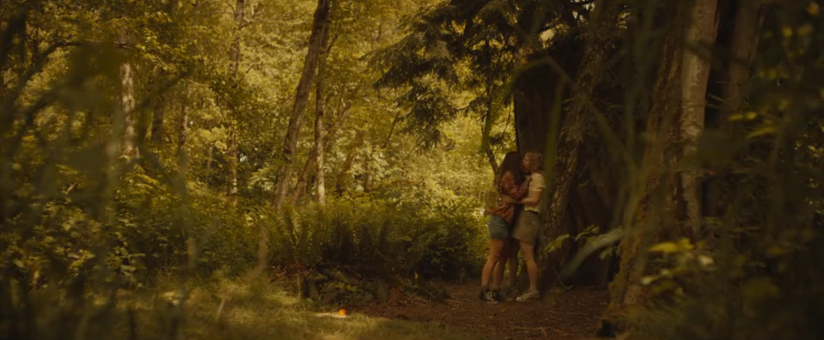 Shauna and Melissa kissing against a tree